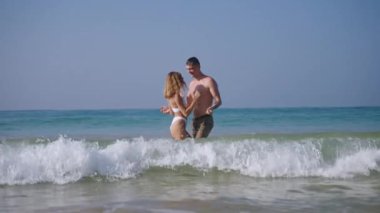Çekici genç çift deniz dalgalarında eğleniyor. Tropik adanın yanındaki okyanusta oynayan sağlıklı bir adam ve kadın. Kız arkadaş, erkek arkadaş huzurlu bir yerde romantik bir gezinin tadını çıkarıyor..