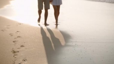 Romantik bir adam, deniz sörfünde el ele yürüyen bir kadın. Okyanus kıyısında rahatlayan hoş bir çiftin yansıması. Erkek arkadaş, kız arkadaş hindistan cevizi kokteyli içer, kumsalda buluşmanın tadını çıkarır..