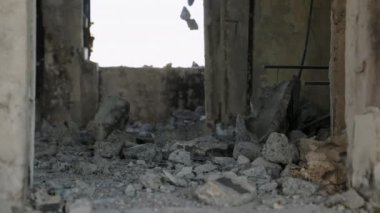 Ağır çekim, yangından kaynaklanan ağır yıkımı ve apartman dairesini bombalamayı gösteriyor. Savaştan zarar görmüş bina içi, Mariupol 'de dökülen beton ve metal çubuklar gösteriyor. Harabeler kentsel bozulmayı vurguluyor. Yavaşla