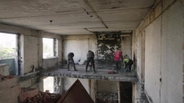 2023-07-30 - Mariupol, Ukrayna. Ekip, yıkılan binanın beton duvarlarını ve tavanlarını yenilemek için kaldırıyor. İnşaat işçileri savaştan zarar görmüş apartmanı aletlerle söküyorlar. Yavaş çekim.