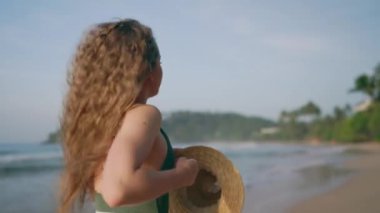 Neşeli kadınlar yaz melteminin, deniz kenarında tatilin tadını çıkarırlar. Sağlıklı dalgalı saçlı, tropik plajda yürüyen, arka planda okyanus dalgaları olan bir kadın. Yaşam tarzı, seyahat, saç bakımı, eğlence konsepti.