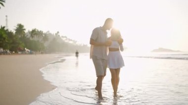 Yeni evli çift deniz sörfünde tropikal hindistan cevizi kokteylleriyle el ele yürür. Romantik aşıklar randevularda eğlenir. Okyanus sahilinin ıslak kumlarında yalın ayak yürüyen insanların silueti..