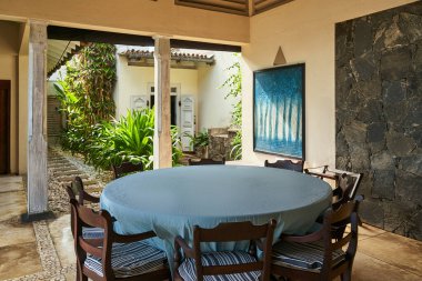 Klasik iç tasarımı olan tropik bir villa. Açık havada sandalyeli yuvarlak masa. Bereketli bir bahçe manzarası var. Rahatlamak ya da yaratıcı bir iş için geri çekilmek..