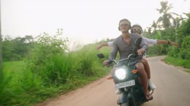 Motosiklete binen mutlu çift. Sevgililer gün batımında motosikletle gezerler. Aşık bir kadın orman yolunda coşkuyla el ele tutuşur ve güler. Güzel turistler bisiklet yolculuğunun tadını çıkarır. Güneş patlamaları