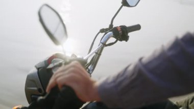 Motosiklet gidonunda motorlu el. Sahilde motosiklet kullanan biri var. Hız göstergesi ve dikiz aynalı bir motosiklet göstergesi. Okyanus kenarında scooter 'da oturan bir adam. Güneş merceği yansımaları parlatır.