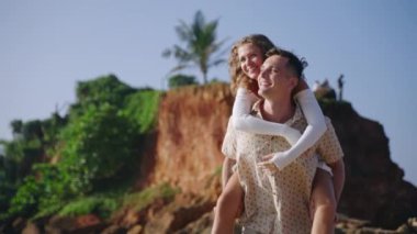 Mutlu koca karısını sırtında taşıyor, tropik kumsalda yalınayak koşuyor. Gülümseyen adam ve kadın okyanus kıyısında eğleniyorlar. Yeni evliler cennet adasında balayının tadını çıkarıyorlar..