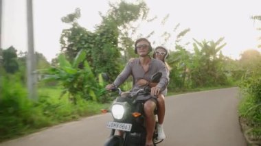 Motosikletli hoş bir çift. Sevgililer motosikletle pirinç tarlasına giderler. Kız arkadaş kollarını açar. Adam ormanda scooter kullanıyor. Gezginler bisikletle adayı keşfeder. Erkek, kadın macerada.