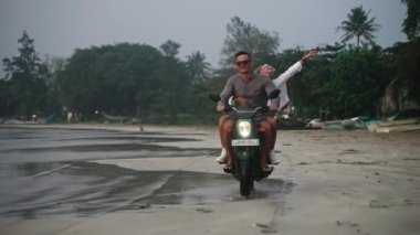Romantik çift gün batımında okyanus sahilinde motosiklet sürüyor. Sevgililer palmiye ağaçlarıyla kıyı şeridinde motosikletle seyahat ederler. Kız arkadaşı erkek arkadaşına sarılıyor, kollarını açıyor, balayı gezisinden zevk alıyor..