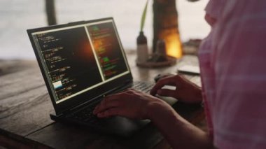 Freelancer program yazılımı, deniz esintisi ve gün batımı titreşimlerini seviyor. Sahil kenarındaki kafede alacakaranlıkta okyanus manzaralı dizüstü bilgisayarda web geliştirici kodları. Uzaktan çalışma, sahil kenarındaki dijital göçebe yaşam tarzı. Yavaşla