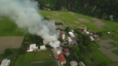 Svan kulesinin Mestia, Svaneti dağları vadisindeki hava manzarası yanıyor. Duman, yakınlardaki tarihi taş kulelerin üzerinden yükseliyor. Acil durum itfaiyecileri cevap verin. Yeşil tarlalar ormanı Georgia 'da dramatik bir sahne.
