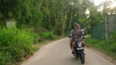 Motosikletle seyahat eden neşeli genç bir çift. İki neşeli aşık orman yolunda motosiklet sürüyor. Kız arkadaş güler, puan kazanır. Gezginler gün batımında scooter kullanır. Erkek, kadın scooter macerası.