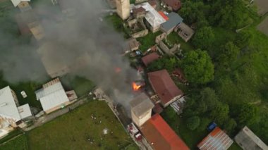 İtfaiyeciler Svan Tower, Mestia 'daki yangını söndürüyor. Duman ve alevler görünür. İtfaiye araçları olay yerinde, insanlar izliyor. Kırsal kesimde eski taş binalar yeşil tarlalar. Havadan çekimler. İHA
