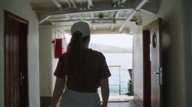 Kıvırcık saçlı kadın okyanusun ufuk çizgisini gözlemliyor. Feribot güvertesinde şapka takan genç bir kadın. Deniz teknesiyle seyahat eder, kıyı şehirlerini keşfeder. Liman manzaralı, hareket halindeki bir gemi limanı..