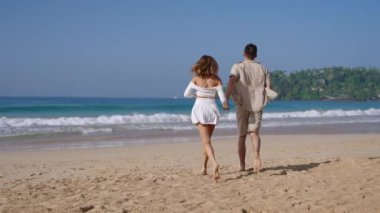 Çekici çift deniz dalgalarında el ele koşuyor. Bronzlaşmış adam ve kadın yaz tatilinde kumsalda eğleniyorlar. Erkek arkadaş, kız arkadaş romantik bir buluşmada. Yavaş çekim, arka plan.