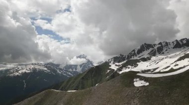 Svaneti 'deki Kafkas dağlarının havası. Sırtta yalnız bir insan figürü. Karla kaplı tepeler, yemyeşil vadiler, dramatik bulutlar. Macera, doğa, yalnızlık. Turizm, belgesel ve seyahat markaları için mükemmel..