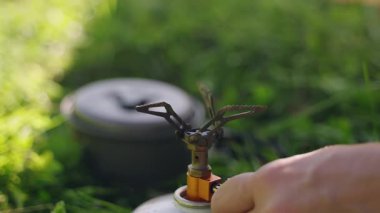 Kişi taşınabilir gaz sobasını çakmakla tutuşturuyor. Kullan at telefondan esrar pişirmek. Doğada açık hava yemekleri. Kamp, yürüyüş, seyahat, çevre dostu geziler, şebeke dışı hafif ekipman maceraları için. Yavaş çekim.