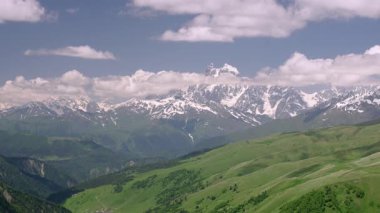 Svaneti 'deki Büyük Kafkas Dağları' nın manzarası. Karla kaplı tepeler, yeşil vadiler, bulutların altında yuvarlanan tepeler. Seyahat için doğal manzara, doğa aktiviteleri. Yavaş çekim.