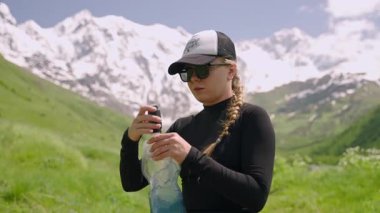 Dağlardaki kadın yürüyüşçü, taşınabilir su filtresini çevre dostu yumuşak şişeye takıyor. Nehirden su topluyor. Açık hava macerası, yürüyüş ekipmanları, susuzluk, doğa kendi kendine yetebilme vahşiliği. Yavaşla