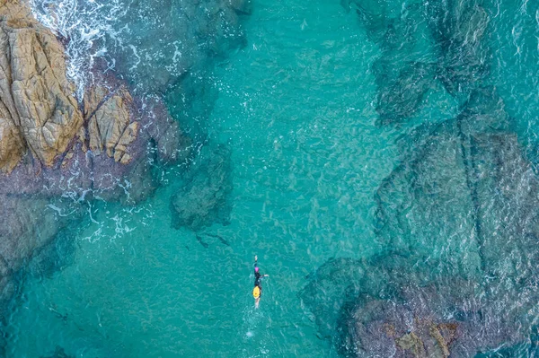 Landscape of aerial top view from drone of a swimmer in open water with wetsuit and buoy