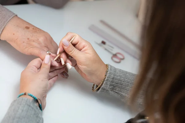 Stock image Close-up of a beautician using an orange stick in the hand of an elderly woman