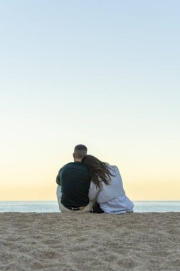 Vertical portrait with copy space of a couple in love very close together on the sand of the beach