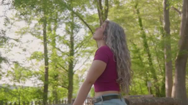 若いです女性とともに灰色の髪で森の中で木を見上げ 彼女の灰色の髪に触れる — ストック動画