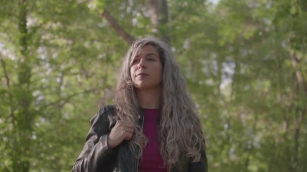 Gri Saçlı Siyah Ceketli Genç Bir Kadın Parkta Ağaçların Altında — Stok video