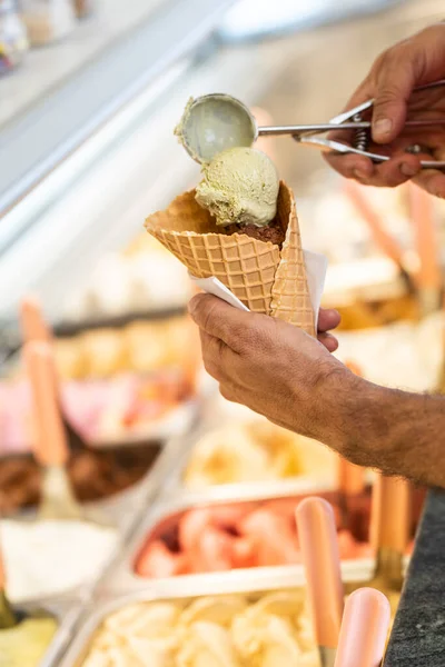 stock image Vertical photo with a close-up of a man preparing a multi flavored ice cream cone