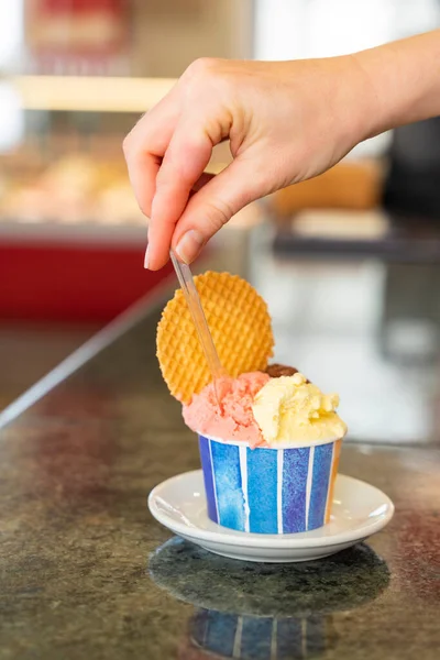 Close-up of a tub of ice cream in two flavors and a cookie over a worktop in an ice cream shop