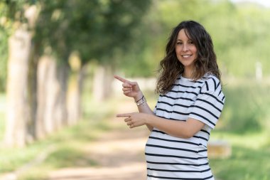 Metin ya da logo eklemek için boş alan olan fotoğraf sol tarafı işaret eden hamile bir kadını gösteriyor