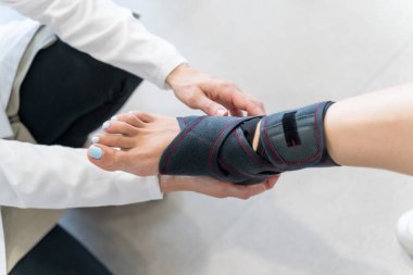 Bir ortopedi dükkanının içinde ayak bilekliği takan bir kadının yakın çekimi var.