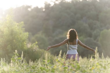 Huzurlu bir çayırda meditasyon yapan genç bir kadınla manzara