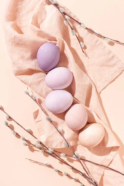 色彩斑斓的复活节彩蛋和柳枝在亚麻布餐巾上 桃色背景 风格简约的流行复活节贺卡 图库图片