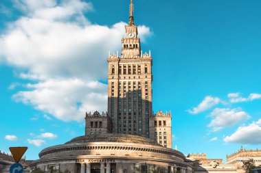 Varşova 'daki Kültür ve Bilim Sarayı' nın üst kısmında büyük kümülüs bulutlu mavi gökyüzüne karşı bir kule ve bir saat var. İmparatorluk mimari tarzı. Avrupa manzaraları, Varşova sembolü..