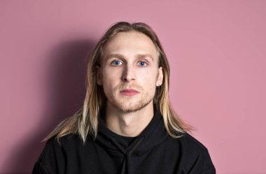 Çok yakışıklı, dalgın, mavi gözlü ve uzun saçlı genç bir adamın portresi. Tam kameraya doğru bakıyor. Yatay, kopyalama alanı, yakın plan, ön görünüm