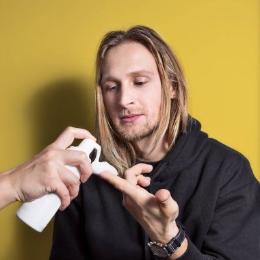 Bir kadının eli kozmetik şişesinden beyaz köpüğü mavi gözlü genç bir sarışının parmağına sıkıyor. Bu süreci izliyor. Erkekler için kozmetoloji, ev cilt bakımı, yakın çekim, kare.