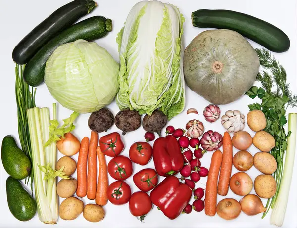 Green and red vegetables are laid out in a gradient at the bottom on a white background. Healthy food concept, organic organic food enriched with vitamins and fiber, top view, horizontal