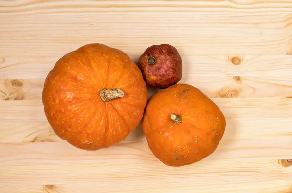 Yellow orange pumpkins and pomegranate on a light wooden table, Halloween concept and autumn pumpkin harvest, farm product, horizontal, top view, copyspace