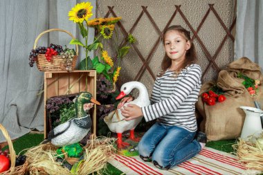 Genç bir kız neşeli bir şekilde bir ördek ve kaz besliyor canlı bir bahçede çiçek açan ayçiçekleriyle dolu. Dost canlısı hayvanlarla etkileşim kurarken gülümseyen kızlar onun mutluluğunu yansıtıyor..