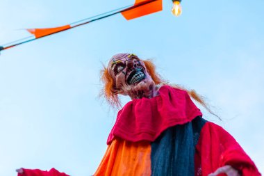 Ürkütücü bir palyaço süslemesi bir ampulle ipten sarkıyor, Cadılar Bayramı partileri ya da her türlü ürkütücü olay için mükemmel. Korku ekle ve bu ürkütücü palyaço dekorasyonuyla ürpertici bir atmosfer yarat..