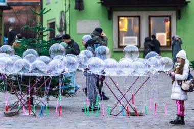 Warsaw, Poland - January 6, 2023. A girl is looking at a variety of glowing balloons at a street fair at Christmas time