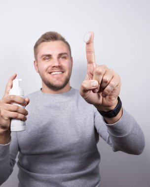 Tıraş köpüğüyle kaplı işaret parmağıyla işaret eden neşeli bir erkek model. Adam beyaz bir arka planda stüdyo ortamında izole edilmiş..