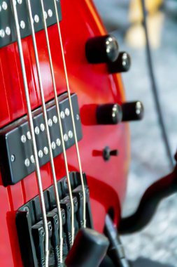 Yakın plan, kırmızı elektro gitarın çarpıcı tasarımını yakalar, parlak vücudunu ve karmaşık sicim düzenini gösterir..