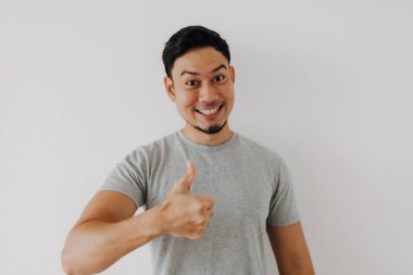 Mutlu Asyalı adam beyaz arka planda iyi bir el işareti olarak baş parmağını gösteriyor..