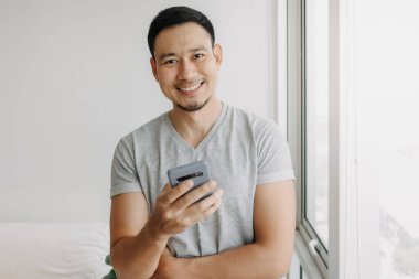 Young happy smiling asian man using smartphone feel relax and comfortable.