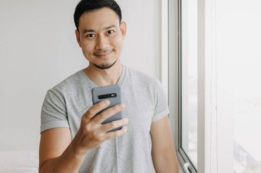 Young happy smiling asian man using smartphone feel relax and comfortable.