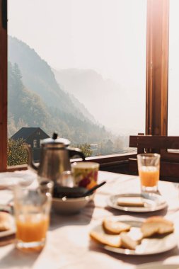 European breakfast set with pancakes juice and honey with sunlight from windows.