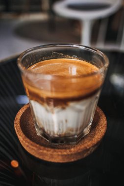 Kafedeki siyah tepside servis edilen şeffaf bardakta kirli kahveyi kapat..