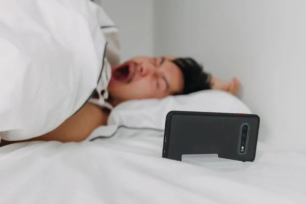 stock image Asian man just wake up and yawn after an overnight video call with his girlfriend.