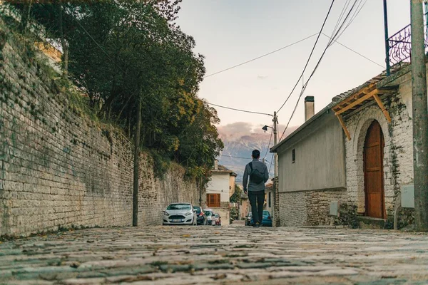 Asian man walking on the street in old town of Gjirokaster, Albania.